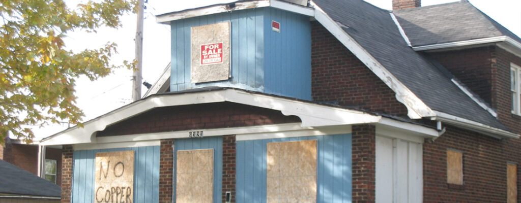 A boarded-up house in Cuyahoga County with the words "no copper" spraypainted on the plywood