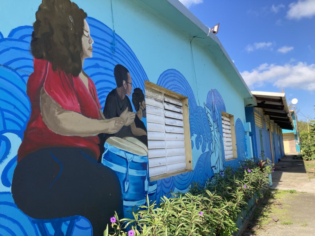 Mural at Centro Comunitario Emiliano Figueroa Torres by artist and CRF fellow Ingrid Pérez. The mural depicts Afro-Puerto Ricans playing the drums on a vibrant blue background.