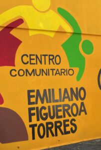 A colorful building exterior depicting figures holding hands around the name of Centro Comunitario Emiliano Figueroa Torres.
