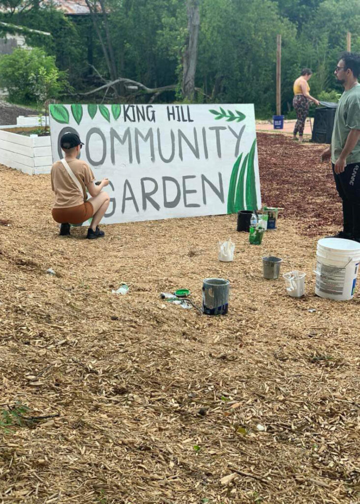 Two volunteers painting a sign at King Hill Community Garden.