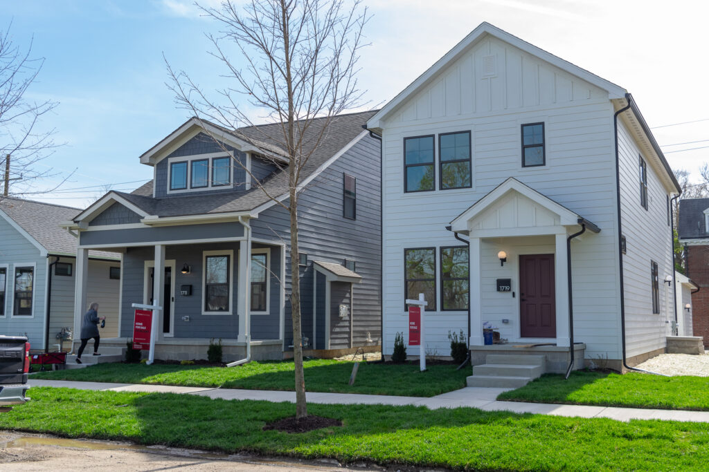 Two newly constructed homes for sale on previously vacant lots in Detroit, featuring modern craftsman-style architecture with gray and white exteriors, front porches, and freshly landscaped yards.