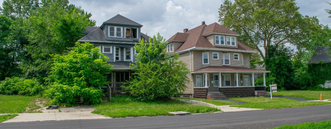 two identical single family houses next to each other, however one is in good condition and up for sale, and one is clearly vacant surrounded by overgrown plants