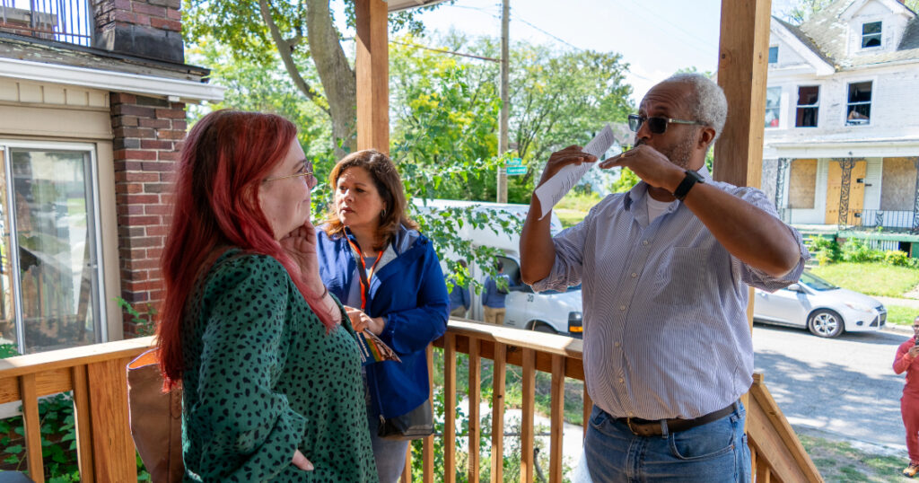 A land bank staff member explains the construction process to a woman on a site tour.