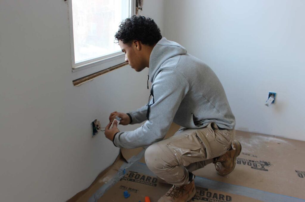 Young man installing an electrical outline in a wall.