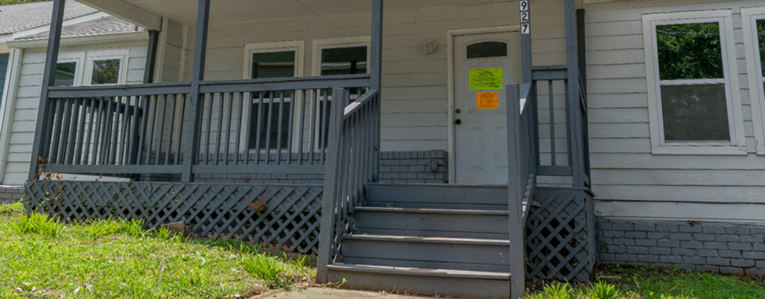 A white house with a code enforcement citation on the door