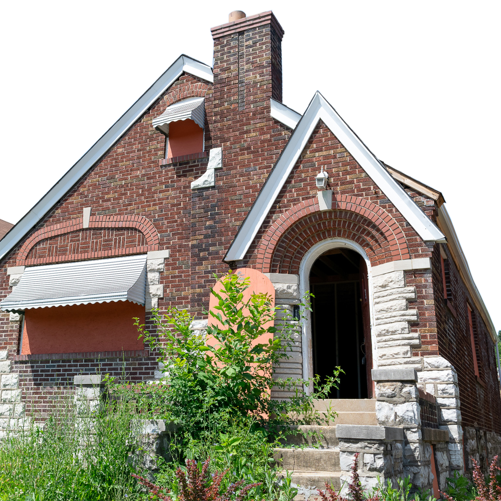 The facade of a vacant brick home in St. Louis with decorative stone detailing, arched entryway, and an overgrown shrub in front of the open doorway.